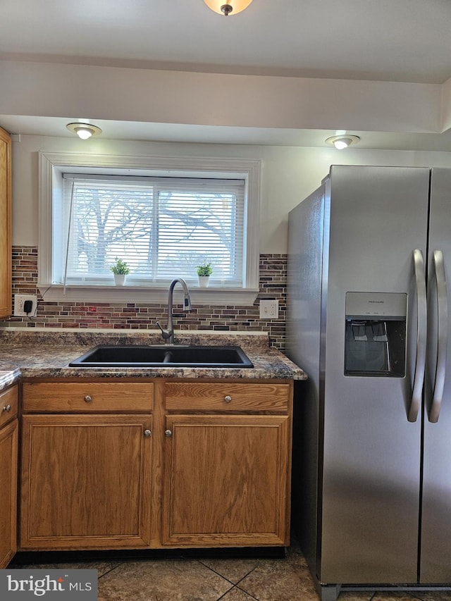 kitchen featuring stainless steel refrigerator with ice dispenser, backsplash, and sink