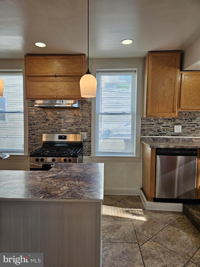 kitchen with backsplash, hanging light fixtures, extractor fan, and appliances with stainless steel finishes