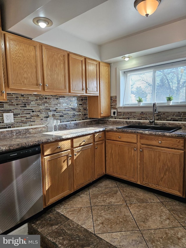 kitchen with backsplash, dishwasher, dark tile patterned flooring, and sink