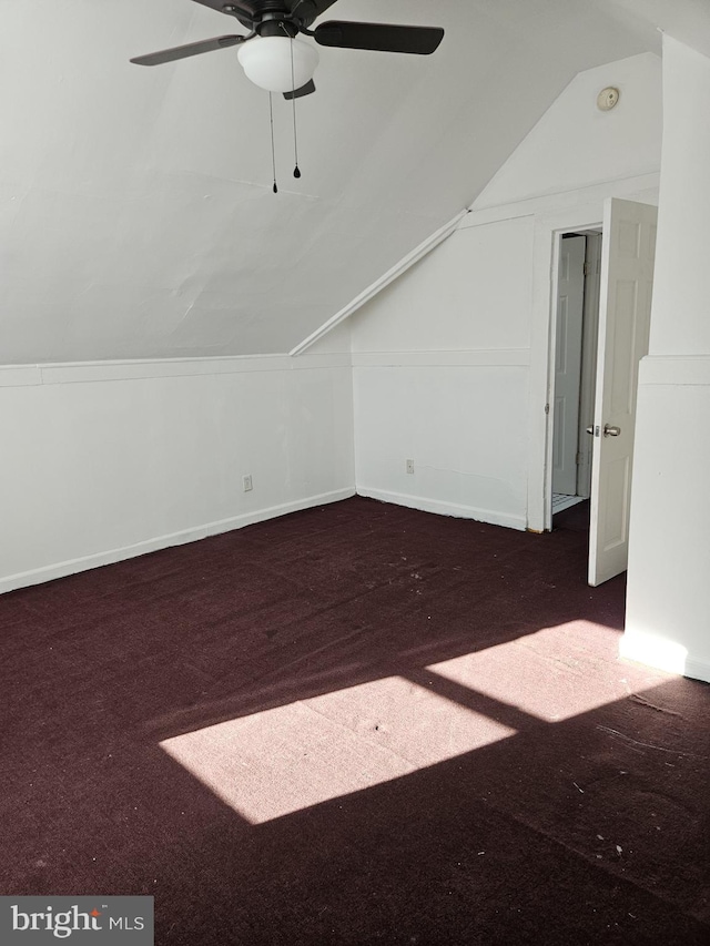 bonus room with dark colored carpet, vaulted ceiling, and ceiling fan