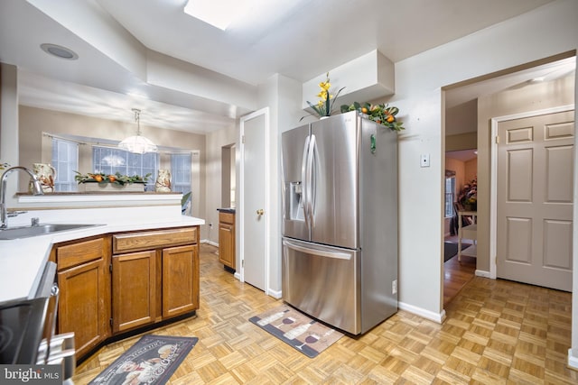 kitchen with sink, light parquet floors, stainless steel appliances, and decorative light fixtures