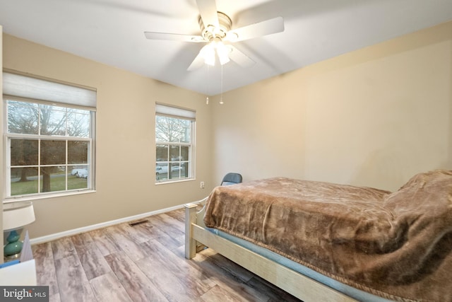 bedroom featuring multiple windows, ceiling fan, and wood-type flooring