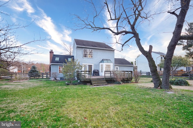 rear view of house featuring a lawn and a wooden deck