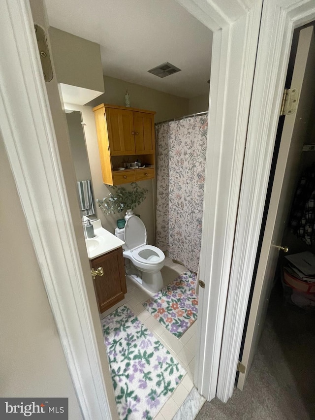 bathroom featuring tile patterned floors, vanity, curtained shower, and toilet