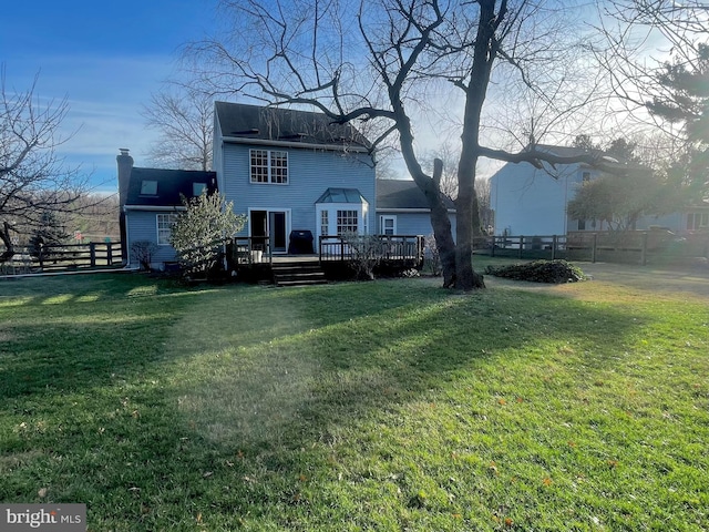 rear view of property featuring a lawn and a deck