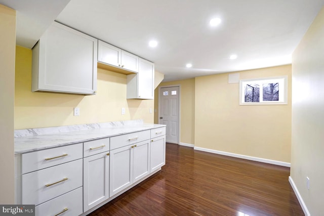 kitchen featuring light stone counters, white cabinetry, and dark wood-type flooring