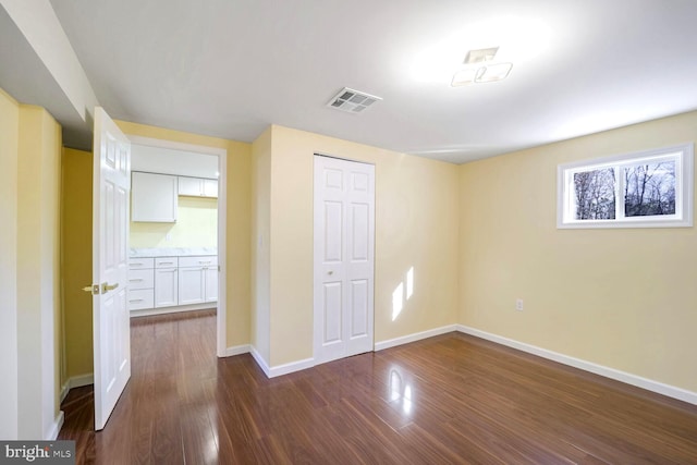 unfurnished bedroom with dark hardwood / wood-style floors and a closet