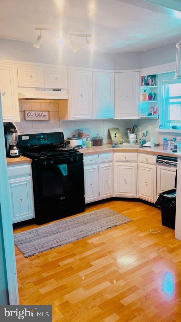 kitchen featuring backsplash, black range with gas cooktop, sink, white cabinets, and light hardwood / wood-style floors