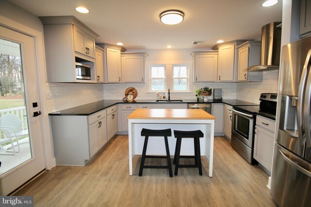 kitchen with sink, stainless steel appliances, plenty of natural light, and wall chimney range hood