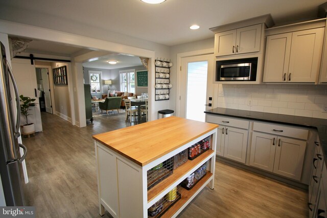 kitchen with gray cabinetry, wood counters, a barn door, and appliances with stainless steel finishes