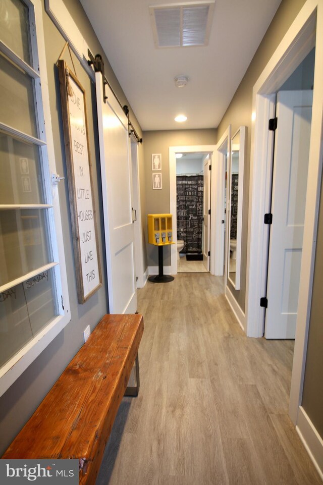 hallway featuring a barn door and light hardwood / wood-style flooring