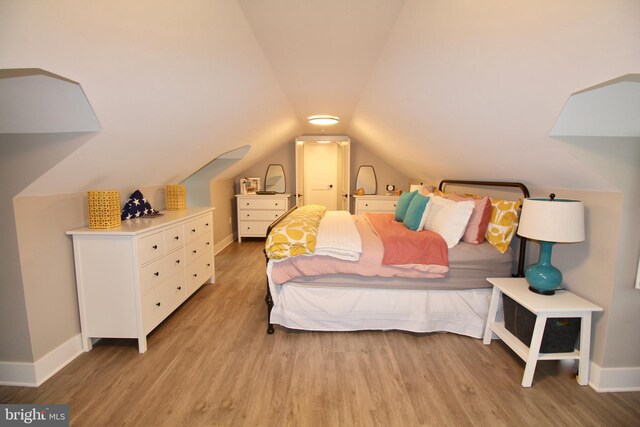 bedroom with light hardwood / wood-style flooring and lofted ceiling