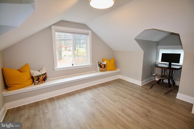 additional living space with hardwood / wood-style floors and vaulted ceiling