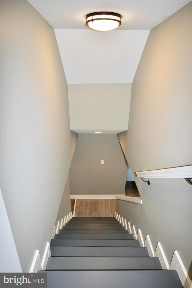 stairs featuring wood-type flooring and vaulted ceiling