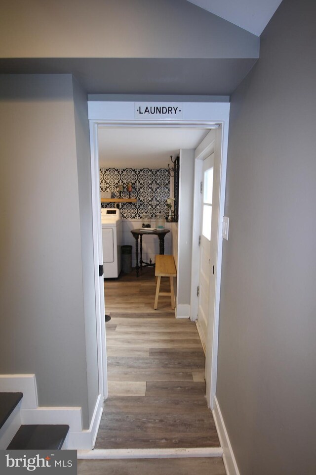 corridor featuring lofted ceiling, wood-type flooring, and washer / clothes dryer