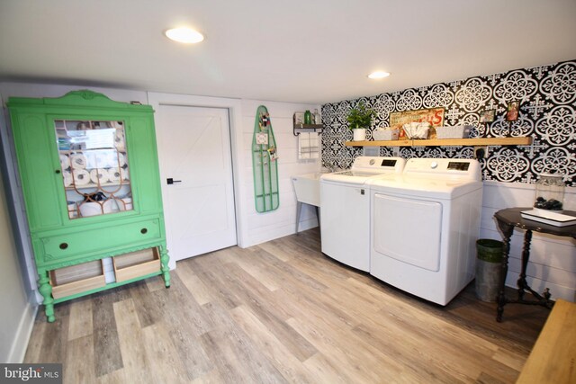 clothes washing area with washer and dryer, light wood-type flooring, and tile walls