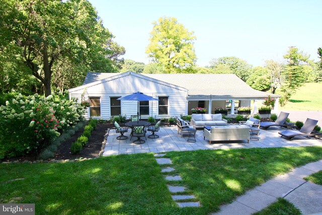 rear view of house with a lawn, an outdoor living space, and a patio