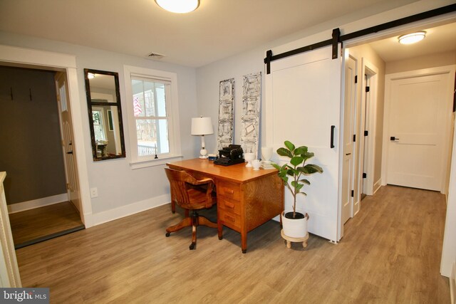 office area with a barn door and light hardwood / wood-style flooring