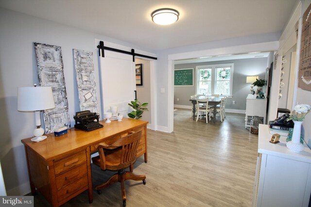 office featuring a barn door and light hardwood / wood-style floors