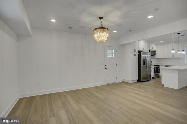 unfurnished living room featuring light wood-type flooring and a notable chandelier