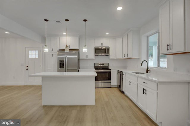 kitchen with a kitchen island, sink, hanging light fixtures, and stainless steel appliances