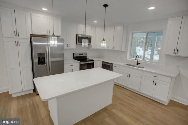 kitchen with sink, white cabinets, a kitchen island, light hardwood / wood-style floors, and stainless steel appliances