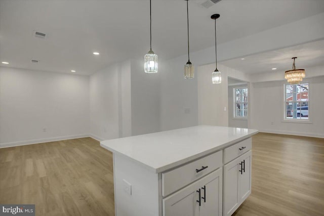 kitchen featuring hanging light fixtures, white cabinets, a center island, and light wood-type flooring