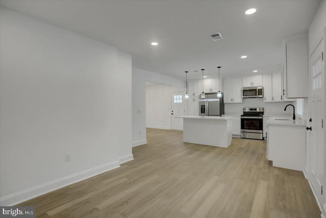 kitchen with a center island, white cabinetry, sink, decorative light fixtures, and stainless steel appliances