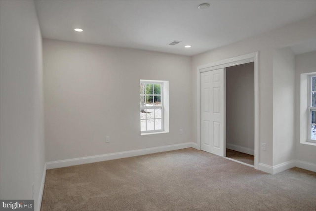 unfurnished bedroom featuring a closet and light colored carpet