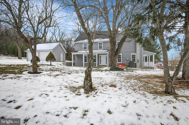 snow covered rear of property featuring covered porch