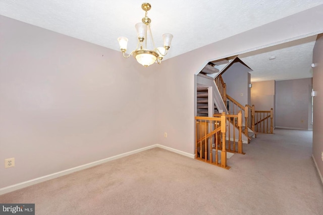 carpeted empty room with a textured ceiling and an inviting chandelier