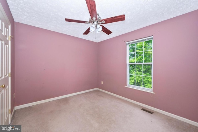 spare room featuring ceiling fan, light colored carpet, and a textured ceiling