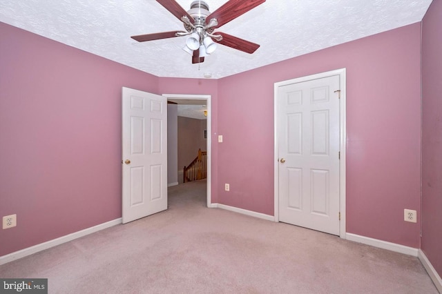 unfurnished bedroom featuring ceiling fan, light colored carpet, and a textured ceiling