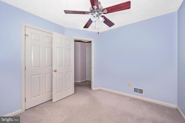 unfurnished bedroom featuring a textured ceiling, ceiling fan, and light carpet