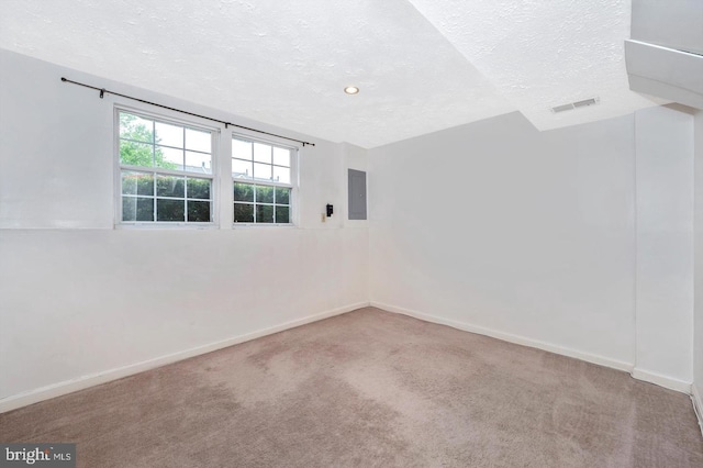 carpeted spare room featuring a textured ceiling and electric panel