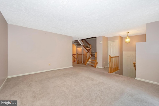 carpeted spare room featuring a textured ceiling and a chandelier