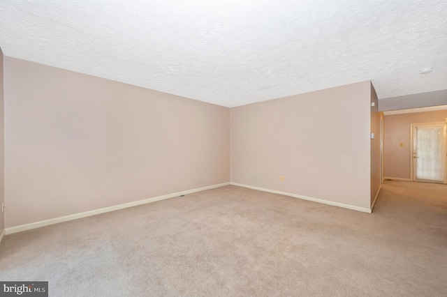 unfurnished room with light colored carpet and a textured ceiling