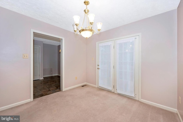 carpeted spare room with a chandelier and a textured ceiling