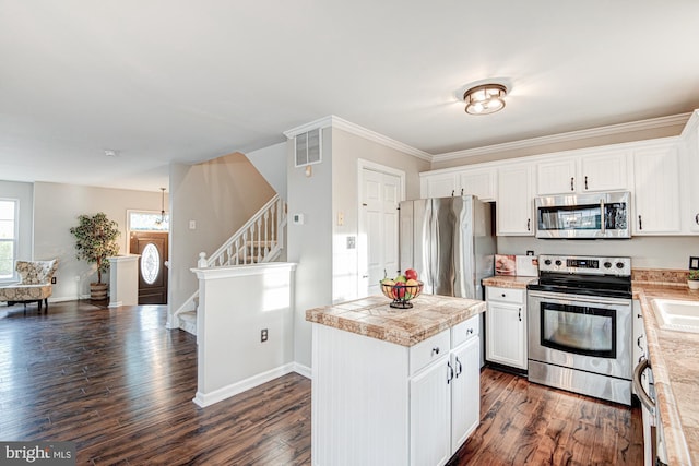 kitchen featuring white cabinets, dark hardwood / wood-style floors, ornamental molding, and appliances with stainless steel finishes