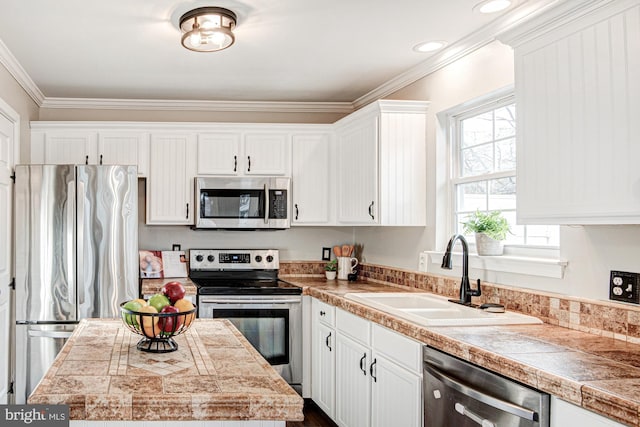 kitchen featuring white cabinets, appliances with stainless steel finishes, crown molding, and sink