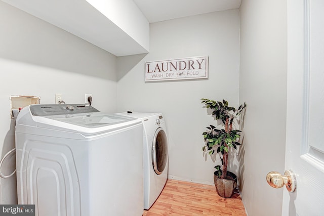 laundry area featuring washing machine and dryer and light hardwood / wood-style floors