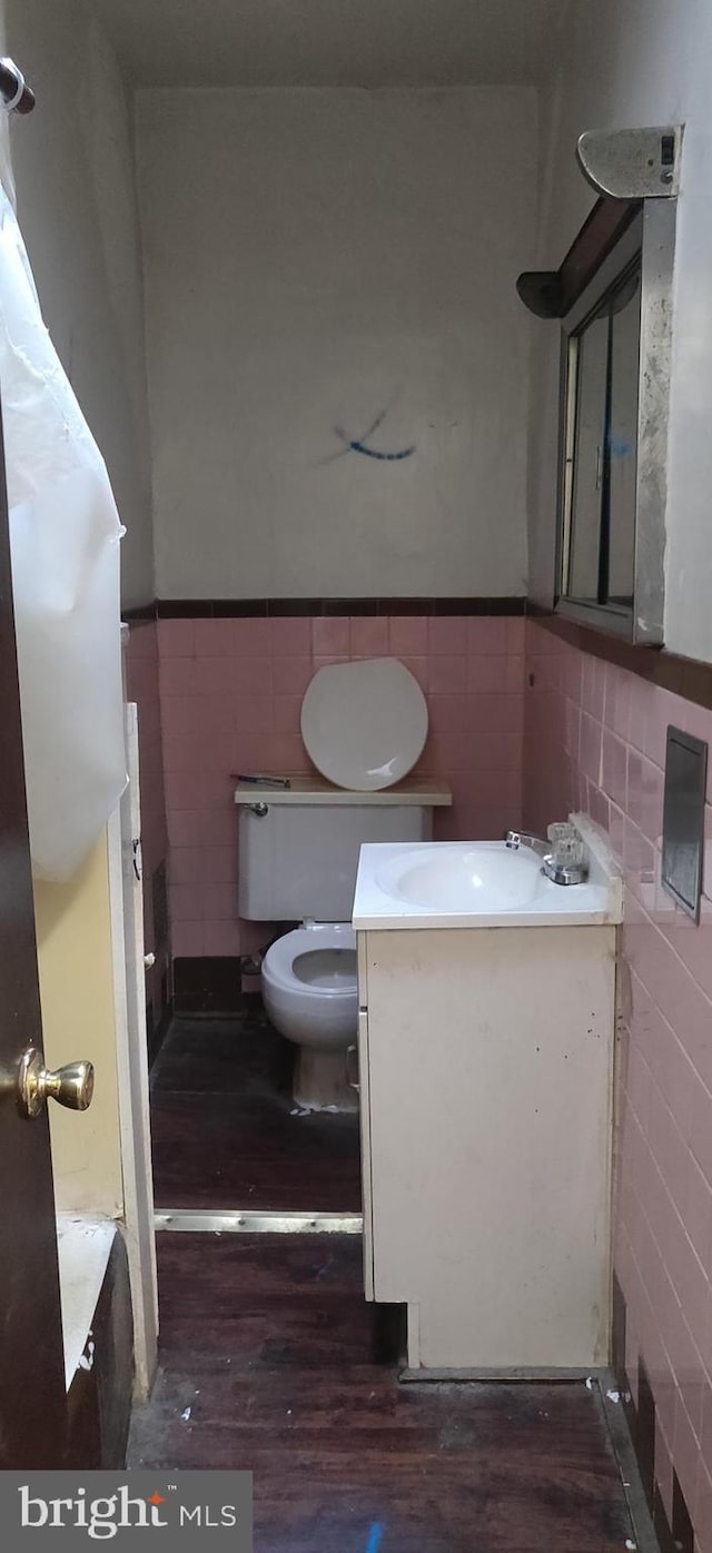 bathroom with vanity, toilet, wood-type flooring, and tile walls