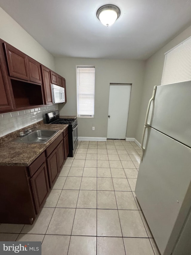 kitchen featuring sink, light tile patterned floors, white appliances, and backsplash