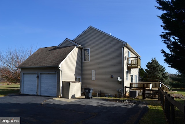 view of side of property featuring a balcony, a garage, central AC unit, and a wooden deck