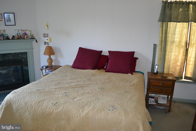 bedroom with carpet floors and a high end fireplace