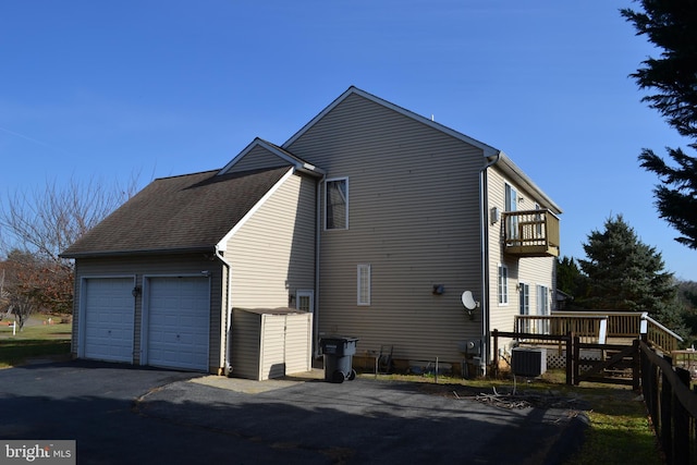 view of property exterior with cooling unit, a balcony, a deck, and a garage