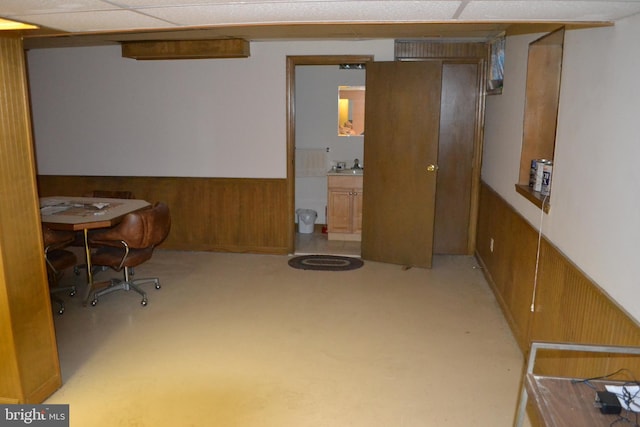 basement with a paneled ceiling and sink