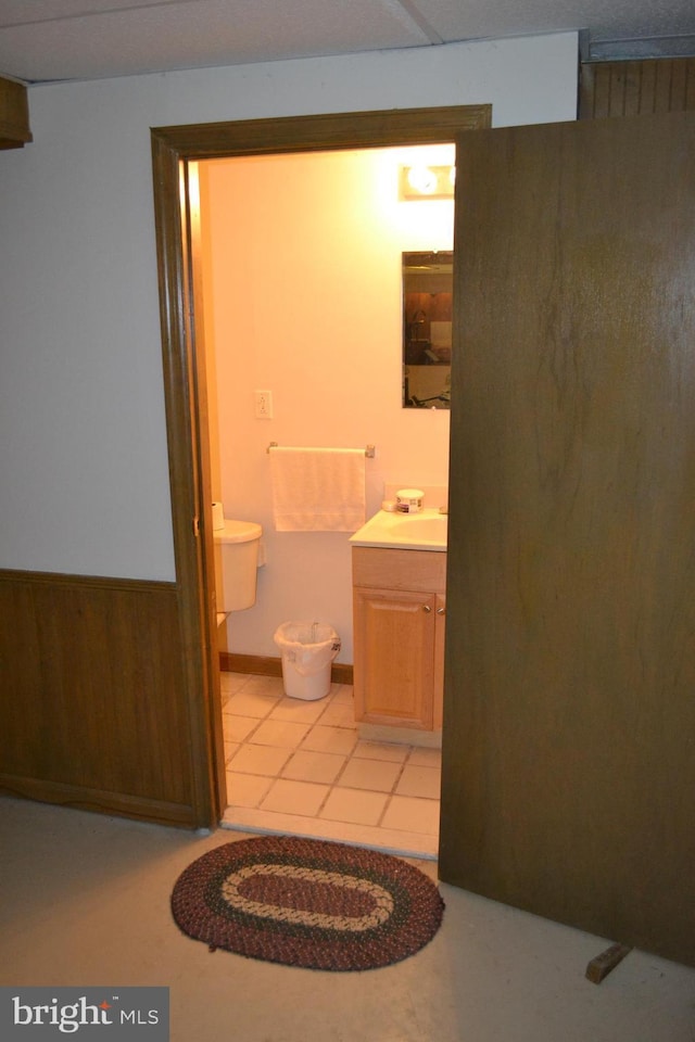 bathroom featuring tile patterned flooring, vanity, and wood walls