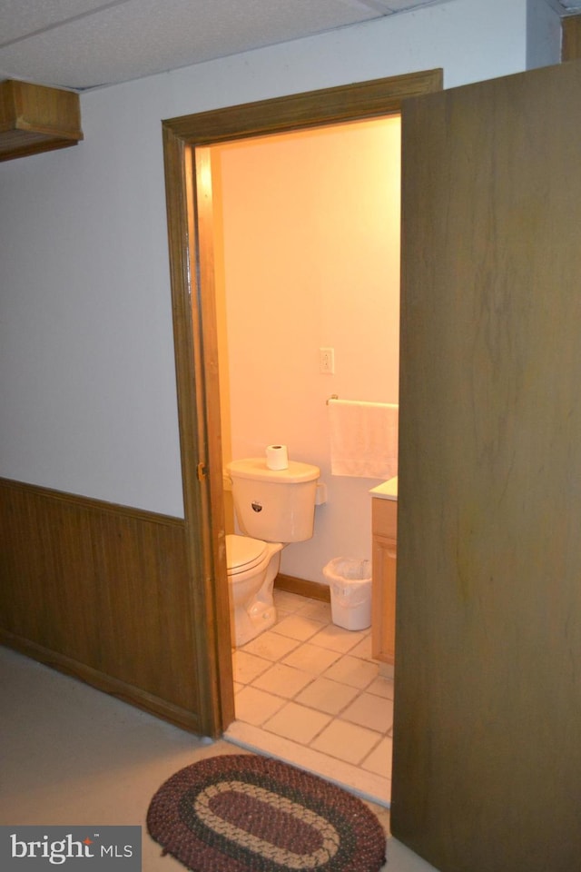 bathroom with wood walls, vanity, and toilet