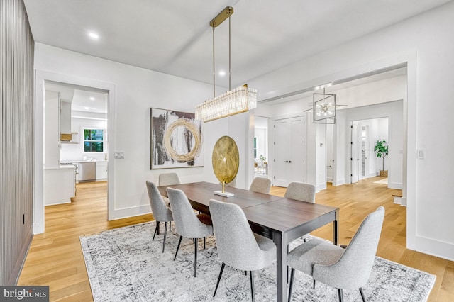 dining space featuring light wood-type flooring and an inviting chandelier